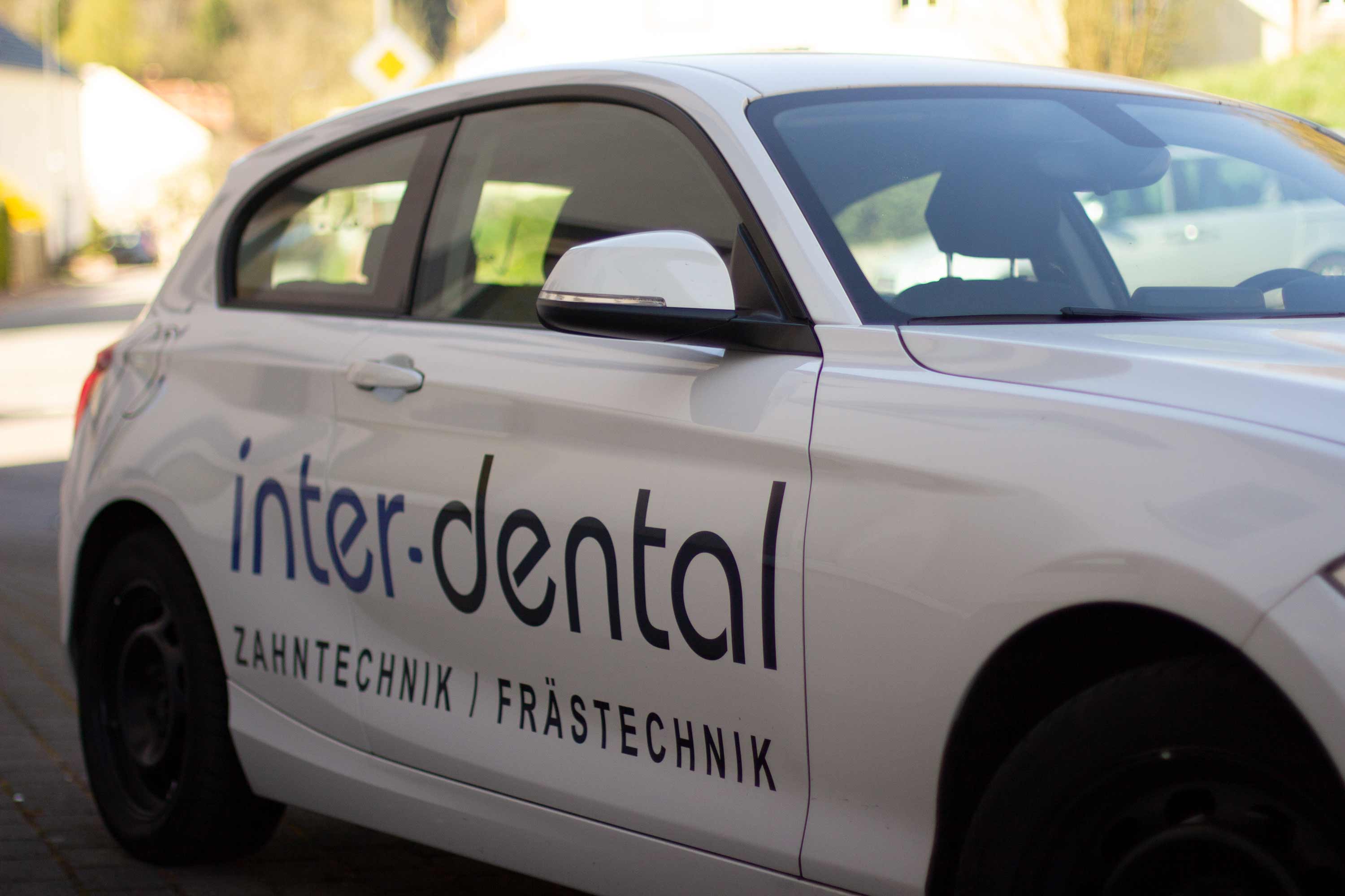 Weißer BMW mit inter-dental-Schriftzug. Eines unserer Firmenfahzeuge.